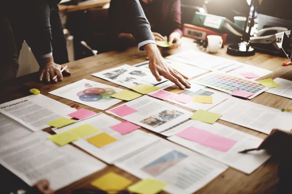 pessoas em volta de uma mesa com papéis cuidando da organização interna de uma empresa