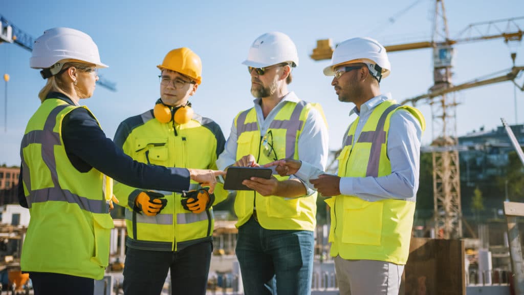 Quatro pessoas conversando em um ambiente de obras.