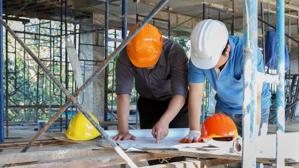 engenheiros analisando plantas em um canteiro de obras