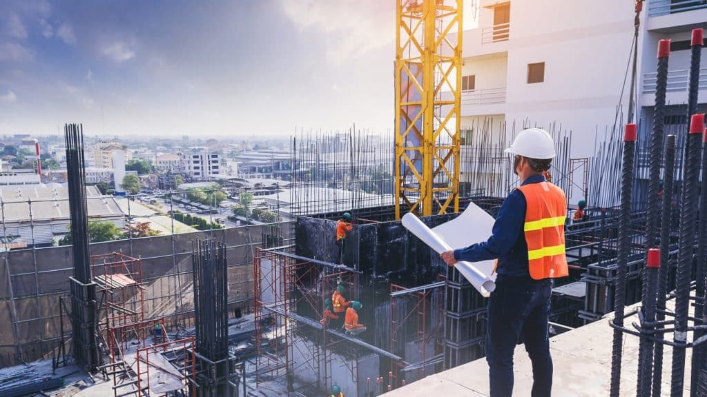 engenheiro observando uma planta em um canteiro de obras